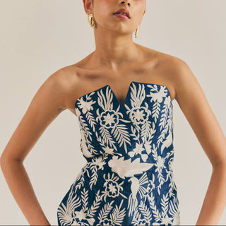 Woman wearing a strapless dress with a floral pattern against a plain background