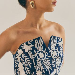 Woman wearing a blue and white floral dress with a neutral background